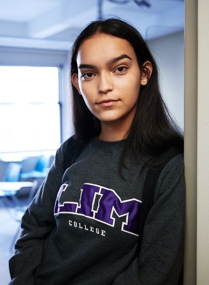 student in classroom doorway wearing LIM shirt