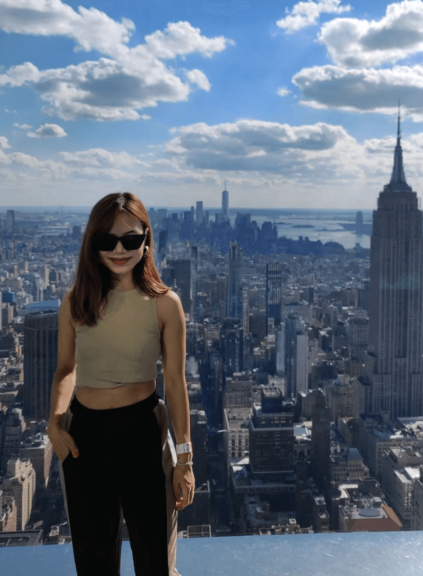 Apurva on skyscraper rooftop with New York City in background