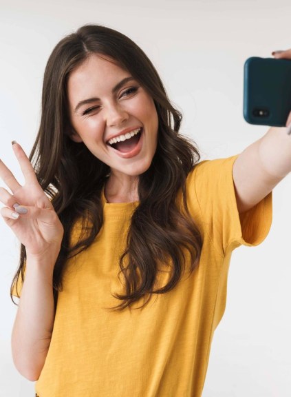 A woman makes a peace sign while taking a selfie