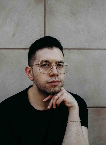 Man posing in front of brick wall