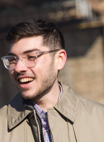 LIM alum Thomas J. Giangrande smiles as he speaks with someone while standing near the Brooklyn Bridge