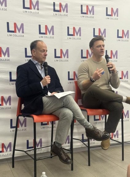 Nate Checketts and Arnie Cohen sit together on high-top chairs during event presentation.