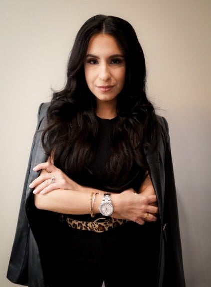 woman, professional photo, dressed in black with jacket folded over shoulders, arms folded