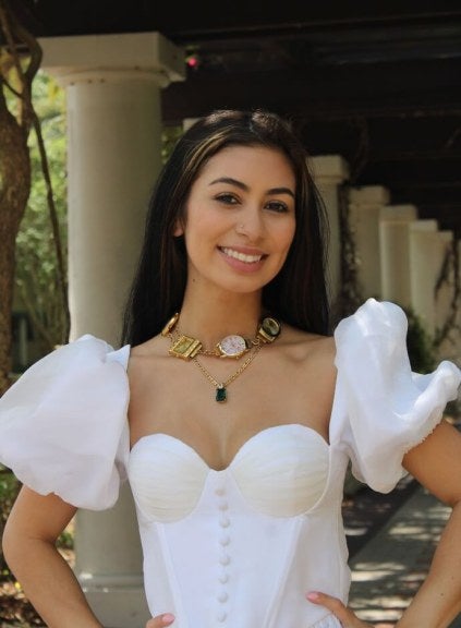 young woman, white formal dress, necklace with thick charms, outdoor environment