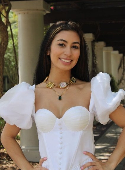 young woman, white formal dress, necklace with thick charms, outdoor environment