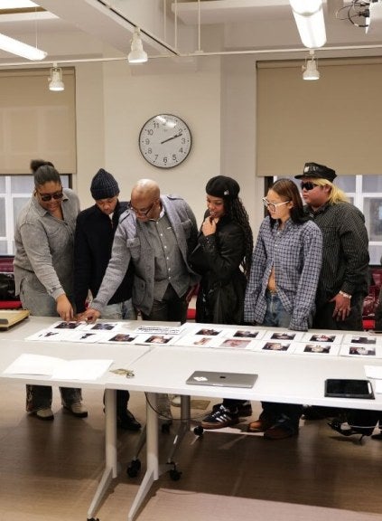LIM student fashion show producers select ESMOD fashions from array of cards laid out on a long white table.
