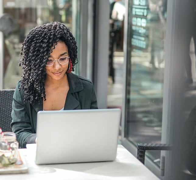 A student working at her computer from a coffee shop.