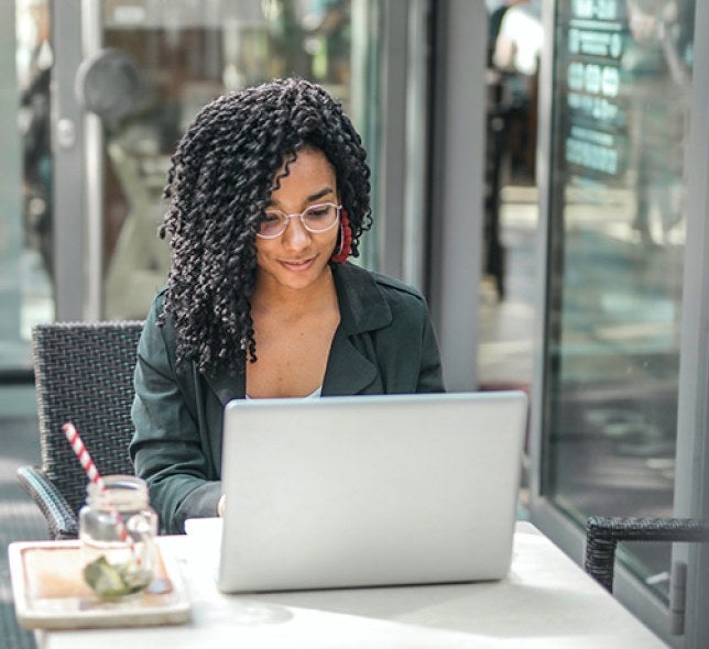 A student working at her computer from a coffee shop.