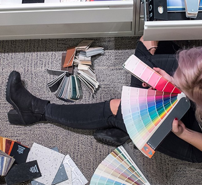 A person on an office floor going through a spread of color pallets.