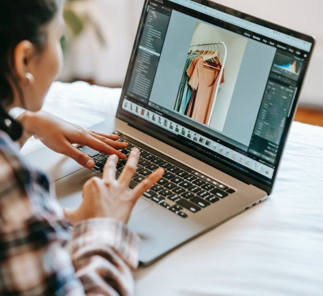 over the shoulder view of person using laptop with image of dresses on rack