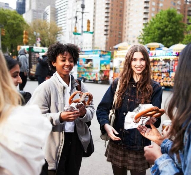 students in NYC with big street vendor pretzels