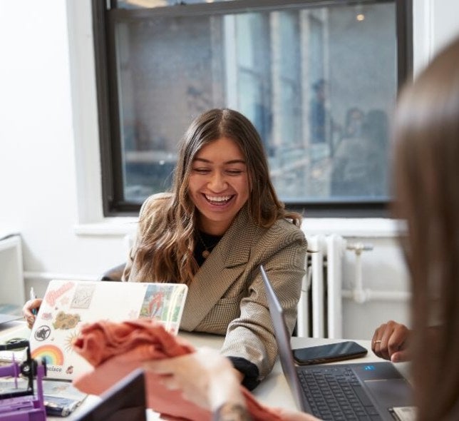 female student in tan jacket in open concept classroom on campus