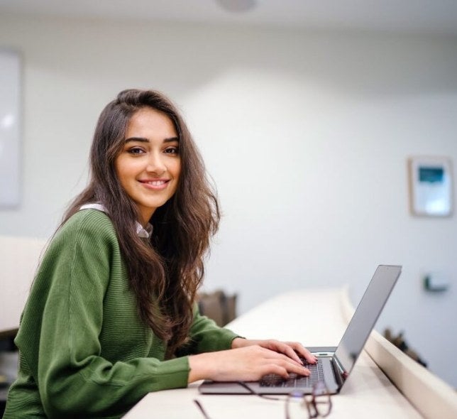 woman brown hair green sweater on laptop in classroom