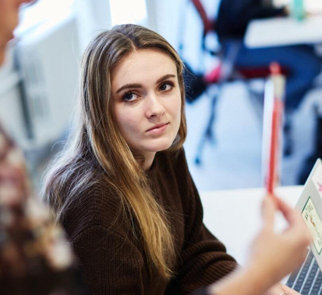 Blonde student in classroom, red sweater