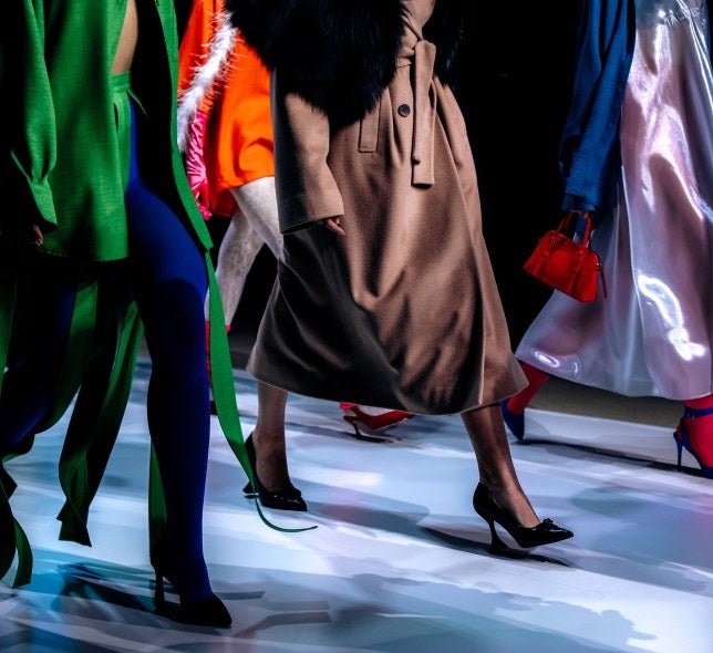 Models from neck down on runway, multicolored clothes and accessories