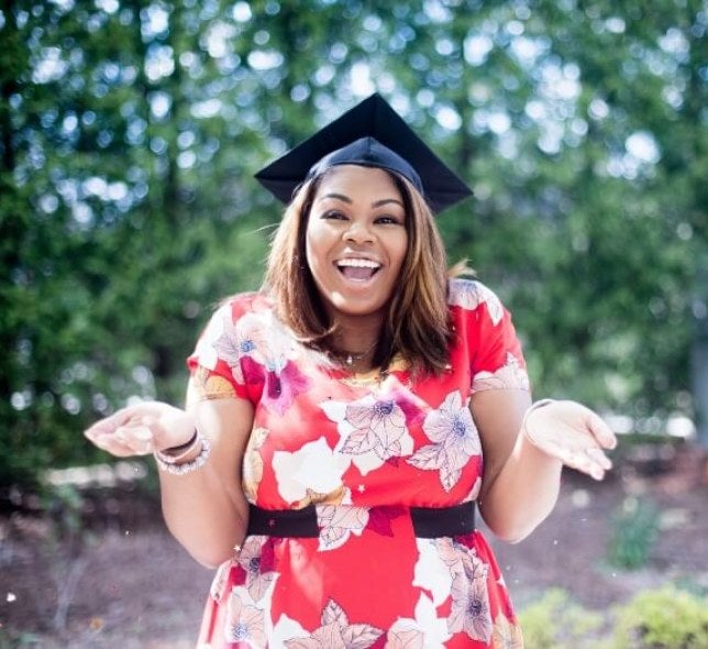 woman in graduation cap, smiling and shrugging
