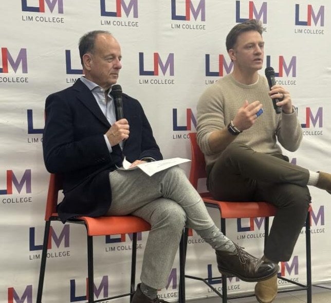 Nate Checketts and Arnie Cohen sit together on high-top chairs during event presentation.