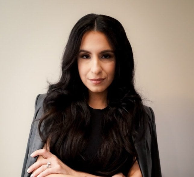 woman, professional photo, dressed in black with jacket folded over shoulders, arms folded