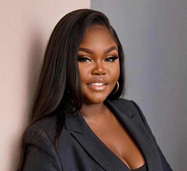 woman with long dark hair, earrings, charcoal business suit, medium shot