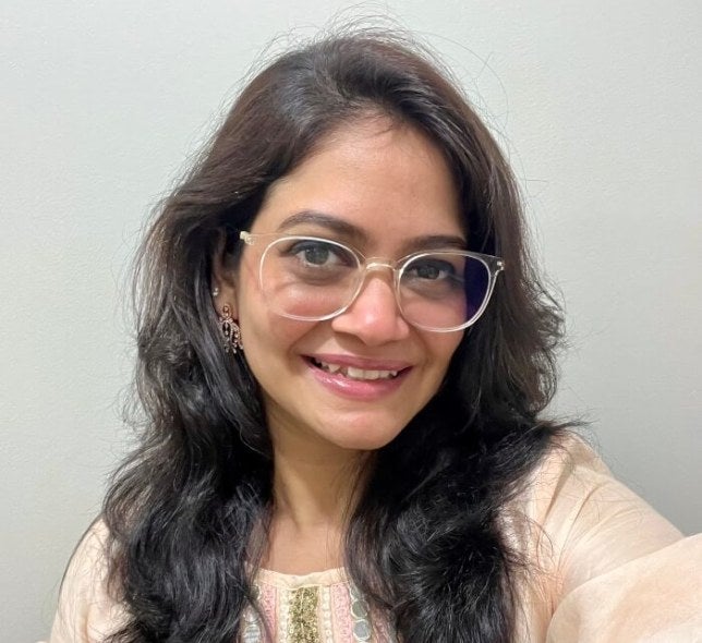 woman, long dark hair, glasses, light-colored blouse, selfie shot