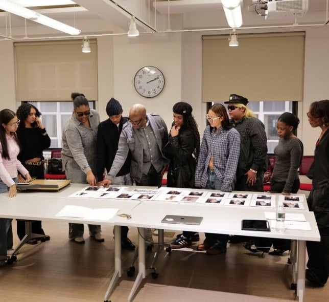 LIM student fashion show producers select ESMOD fashions from array of cards laid out on a long white table.