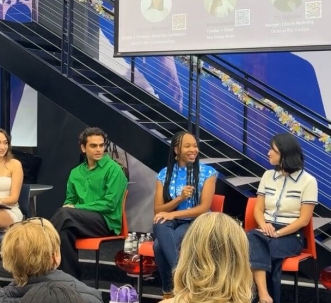 Several LIM College alumni sit on a panel in Maxwell Hall's student center. One of them holds a microphone.