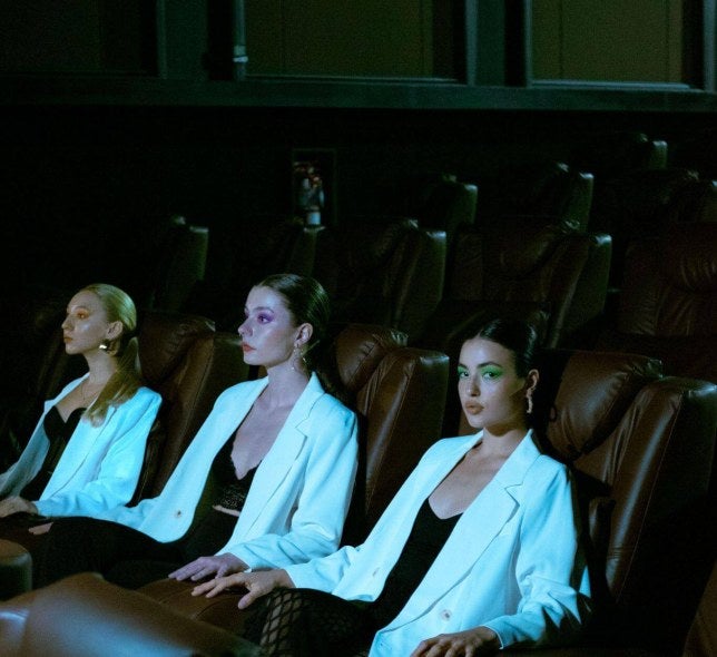 dark viewing theater, female audience members in white blazers