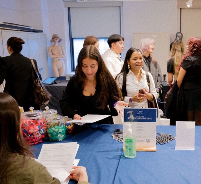 students at career fair table, handing out resume, speaking with employers, LIM classroom