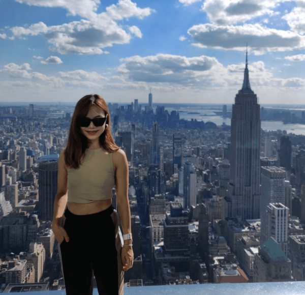 Apurva on skyscraper rooftop with New York City in background