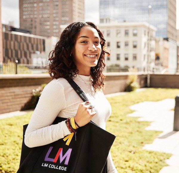 Jesly Cruz smiles while holding carrying an LIM tote bag