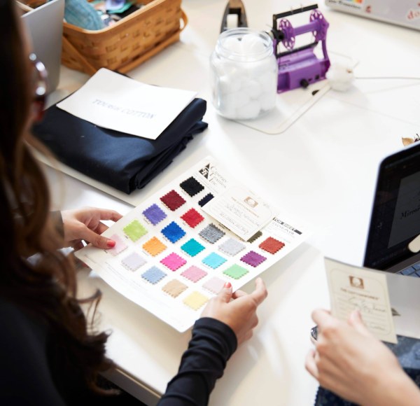 An LIM student holds a piece of paper 25 different-colored cloth samples