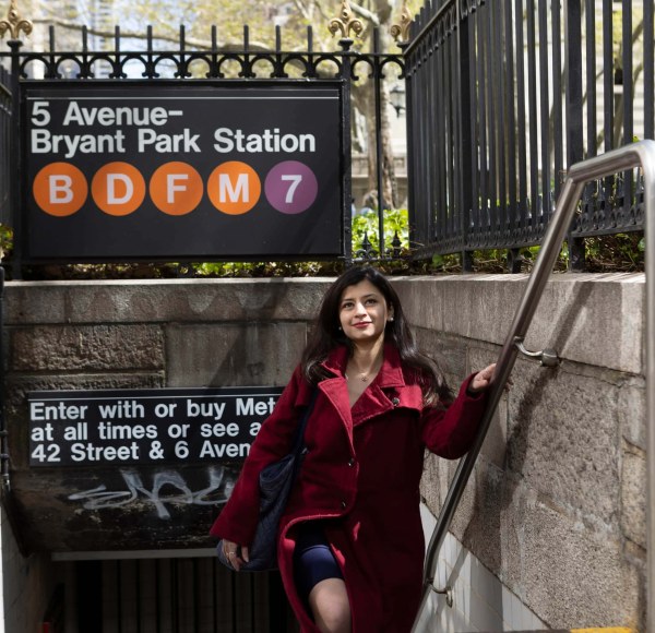 An LIM student wearing a red coat walks out of the Bryant Park subway station