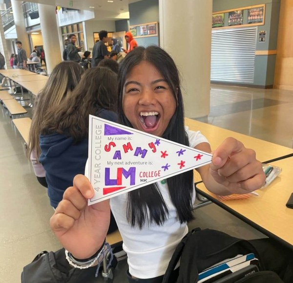 young woman holding up homemade LIM banner celebrating her acceptance