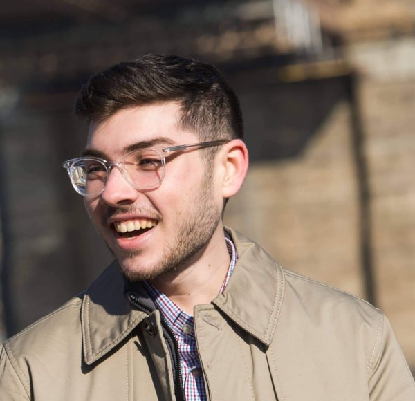 LIM alum Thomas J. Giangrande smiles as he speaks with someone while standing near the Brooklyn Bridge