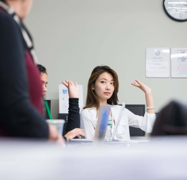 woman in classroom, raised hand