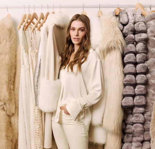 woman in off white in front of a rack of clothes and furs