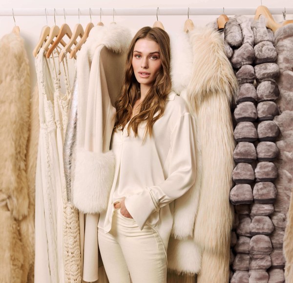 woman in off white in front of a rack of clothes and furs