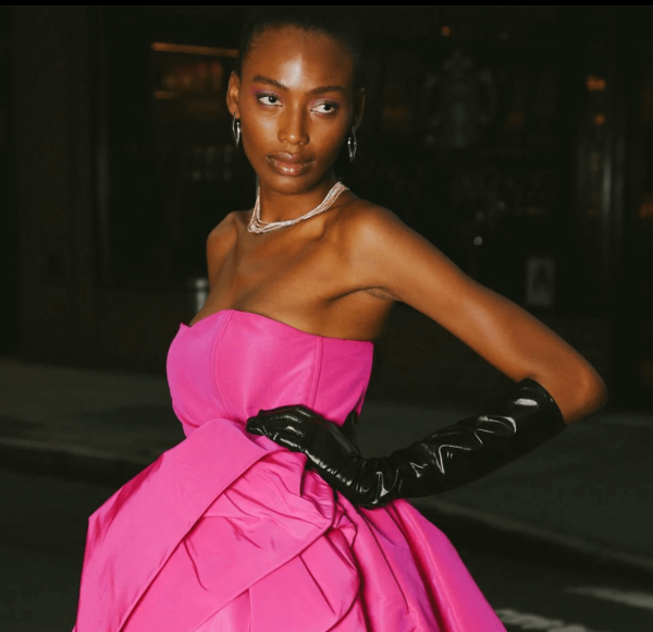 Model in pink dress with black gloves.
