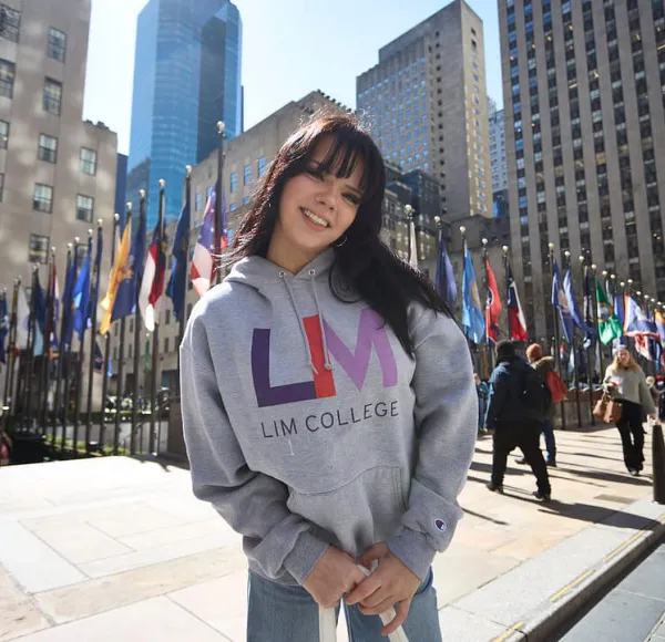 dark-haired young woman in LIM College hoodie, standing outdoors in Rockefeller Plaza