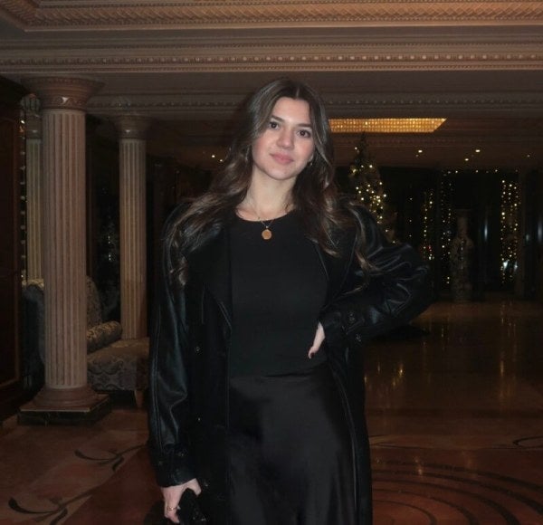 young woman, long brown hair, dressed in back, ornate lobby