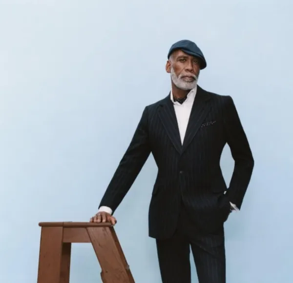 man, white beard, suit, leans against wooden stepladder