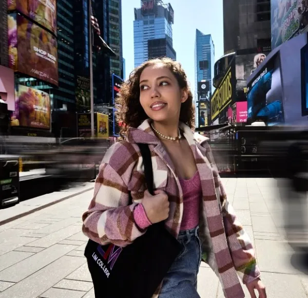young woman, plaid fall coat, LIM tote bag, walks through Times Square in New York City