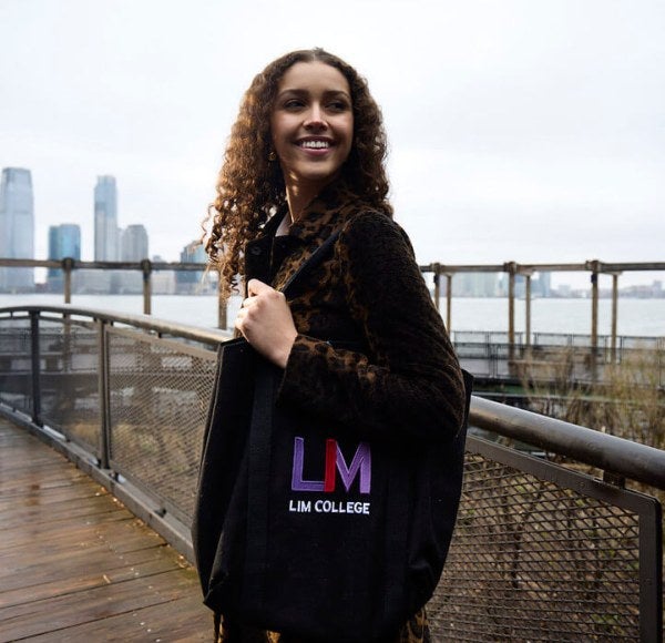 young woman, long brown hair, LIM tote bag, on South Cove Park boardwalk at Battery Park