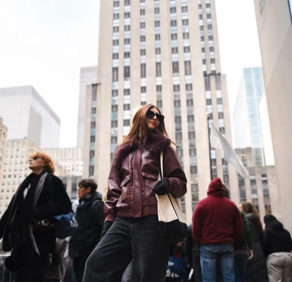 woman, brown leather jacket, standing in Rockefeller Center, New York