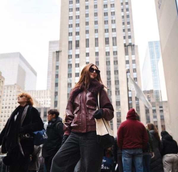 woman, brown leather jacket, standing in Rockefeller Center, New York