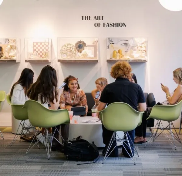 Group of students in 5th Ave lounge, "The Art of Fashion" signage on wall above lightbox displays.