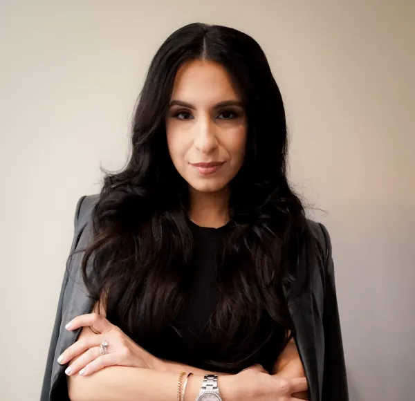 woman, professional photo, dressed in black with jacket folded over shoulders, arms folded