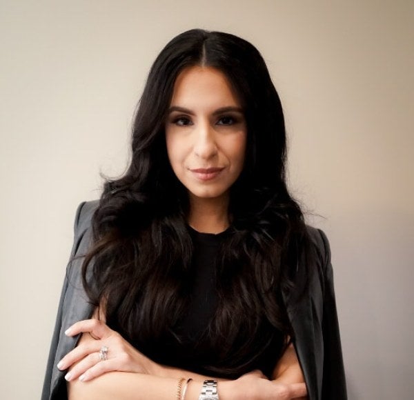 woman, professional photo, dressed in black with jacket folded over shoulders, arms folded