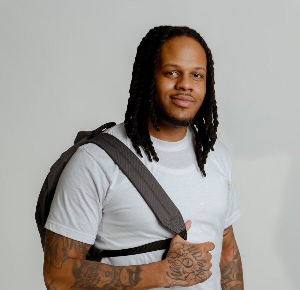 Young man, shoulder-length back hair, white t-shirt, backpack