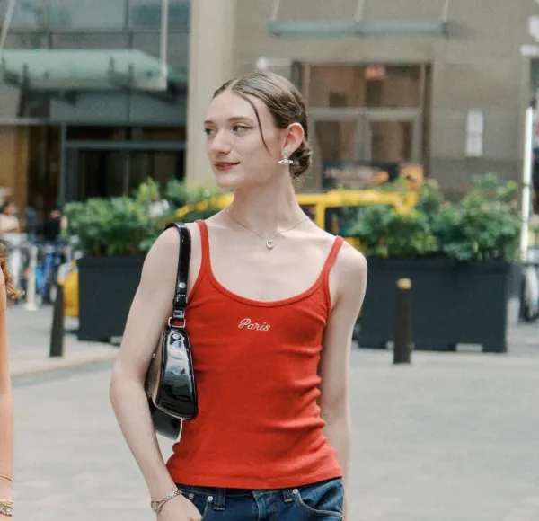 Young woman, red tank top, jean skirt walks in Rockefeller Center